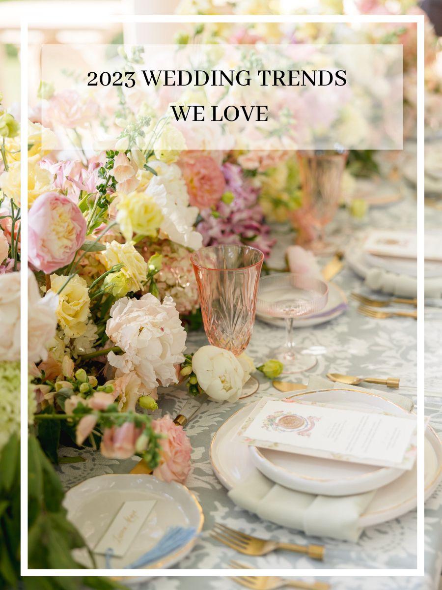 wedding table decor with large colorful floral arrangement and colored glassware, showing two 2023 wedding trends.