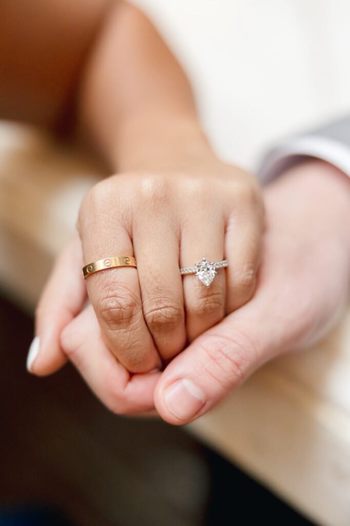 Couple holding hands at bar showcasing engagement ring